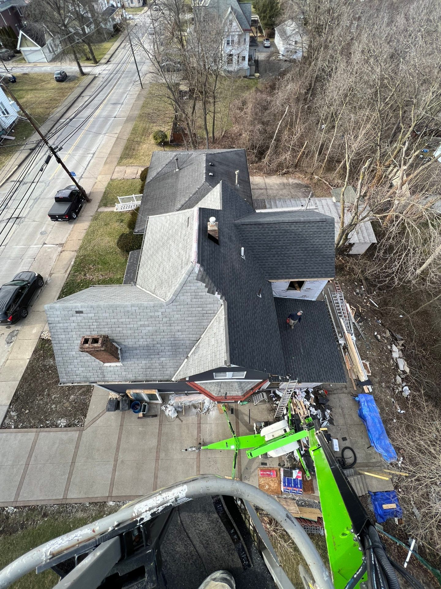 Drone view of a large residential roof replacement with a boom lift staging materials
